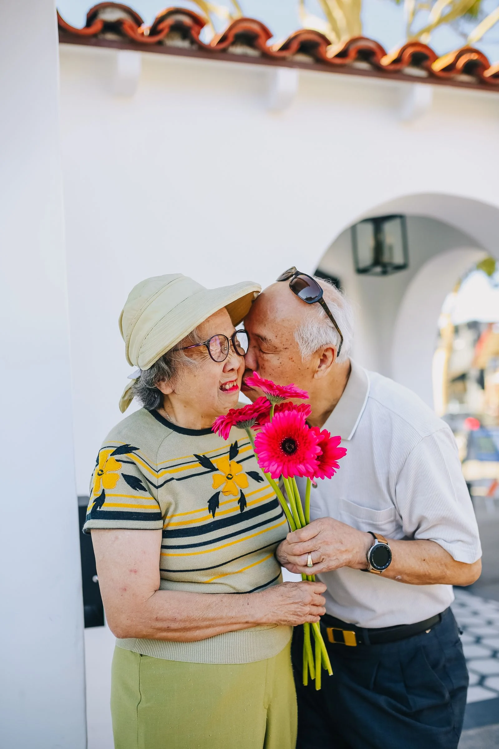 An older couple sharing an affectionate moment with flowers outdoors.