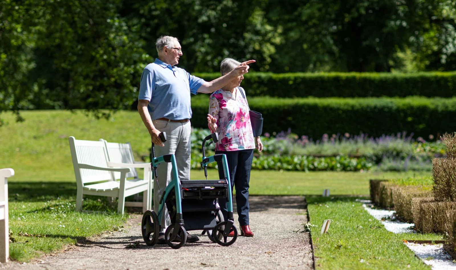 Two older adults outdoors beside a walking aid.