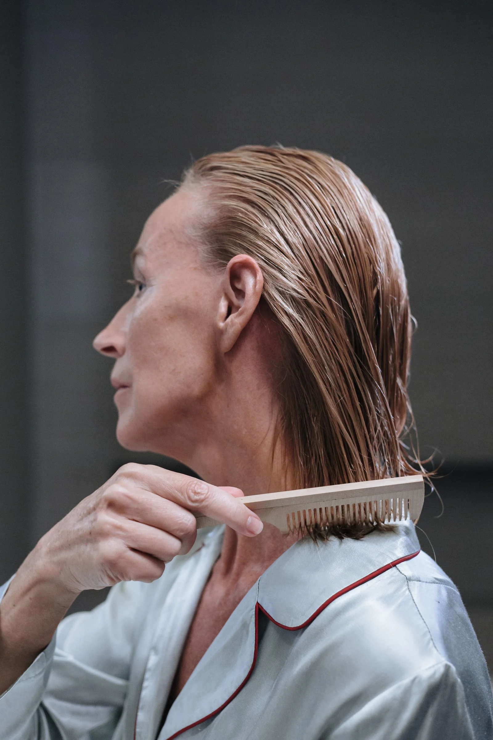 An older woman combing her hair as part of her daily routine.