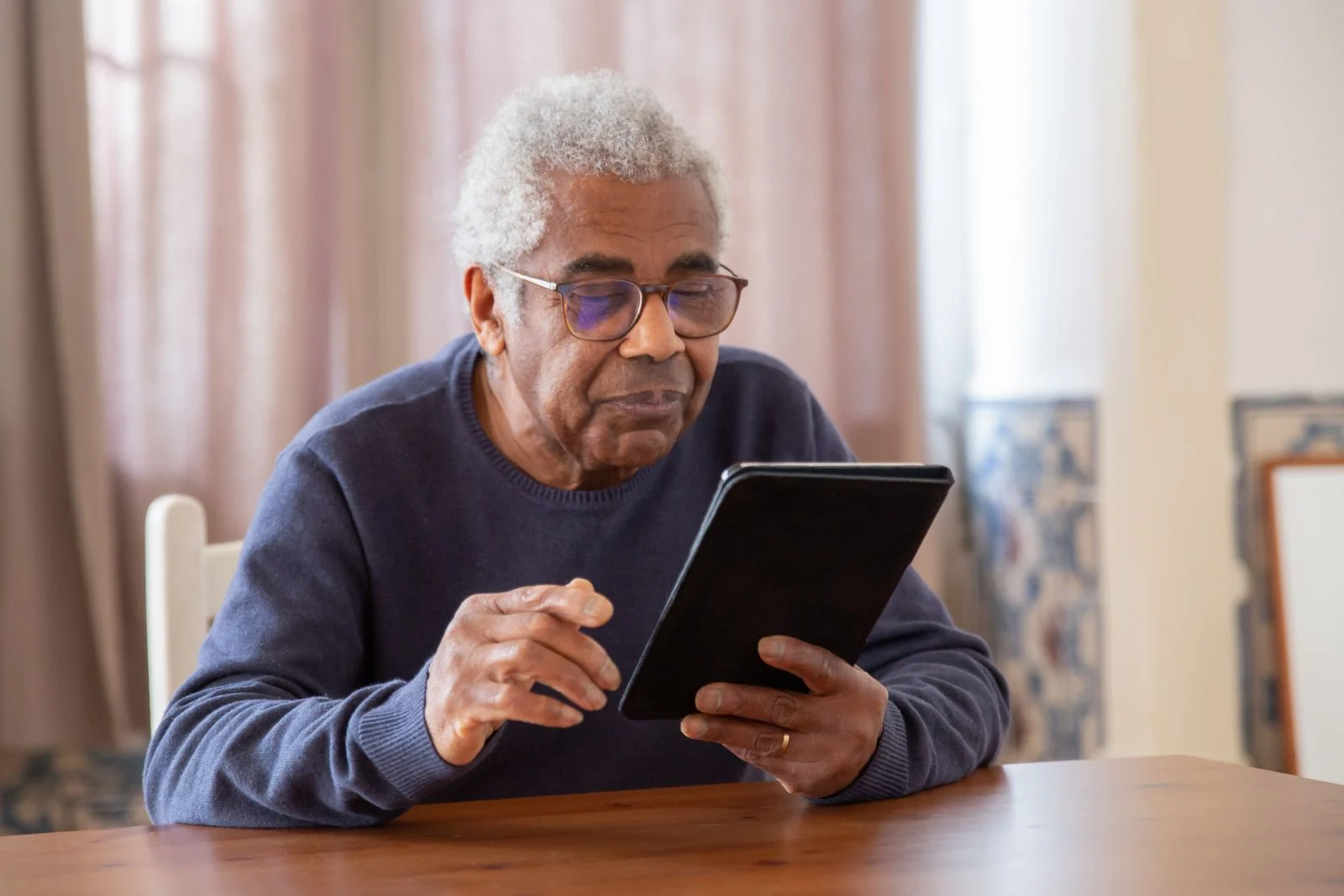 An older adult using a tablet at home.