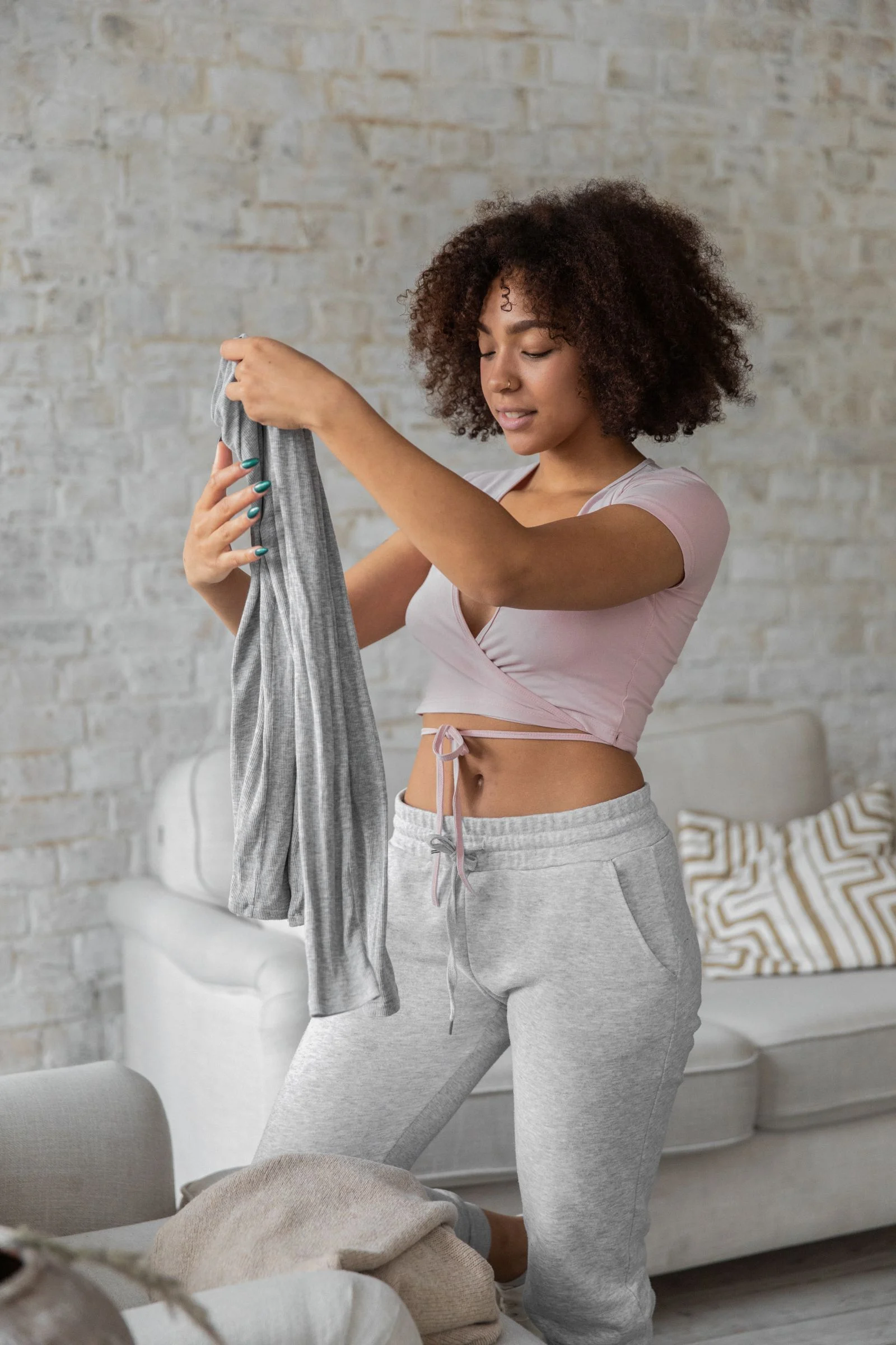 A woman folding clothes in a living room.