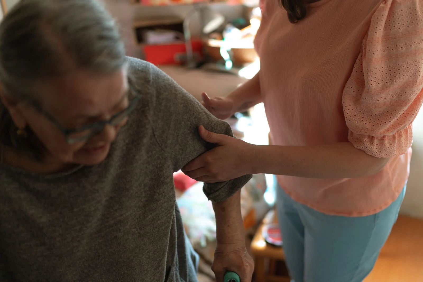 An older woman receiving assistance with movement at home.