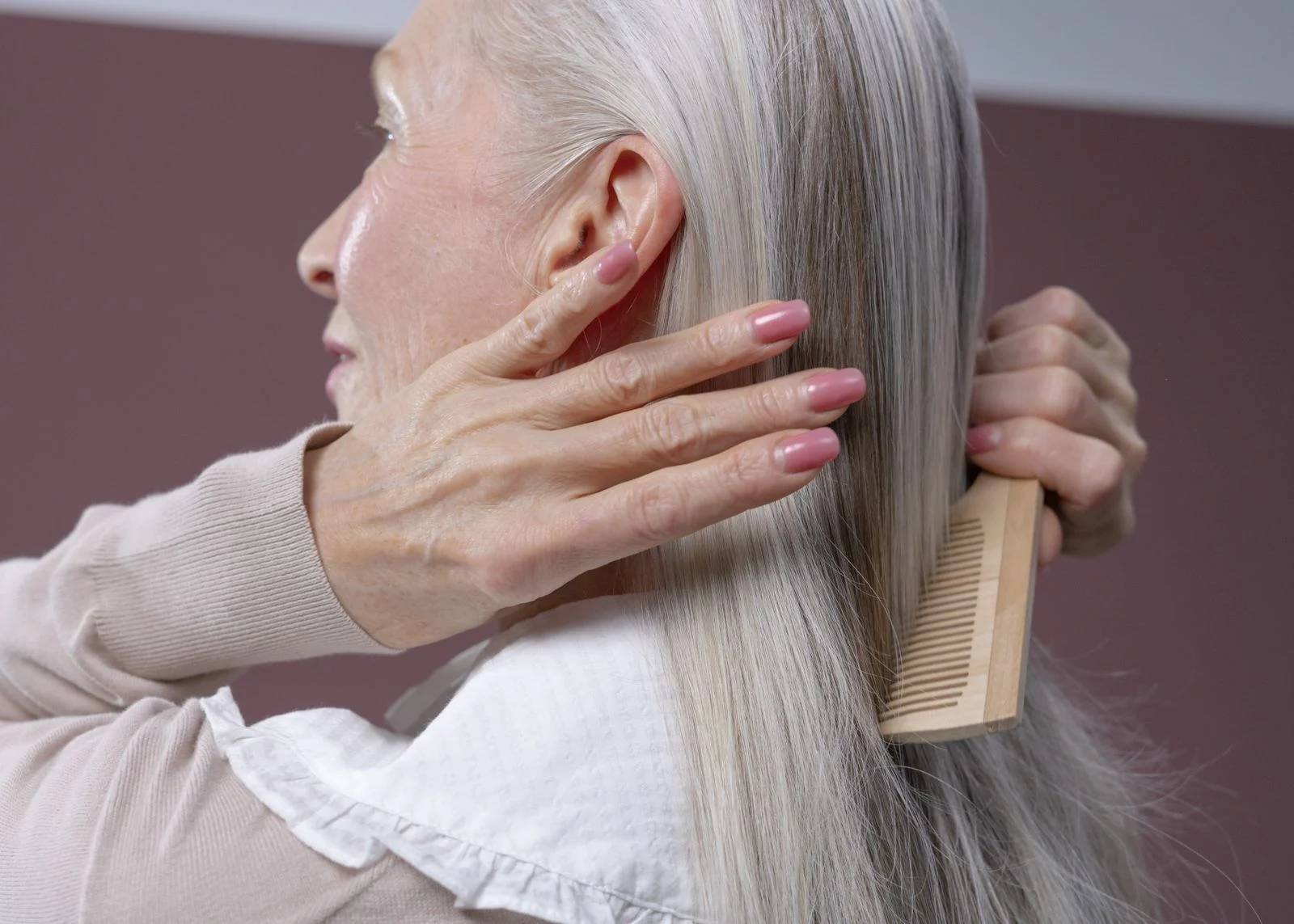 An older woman brushing her hair.