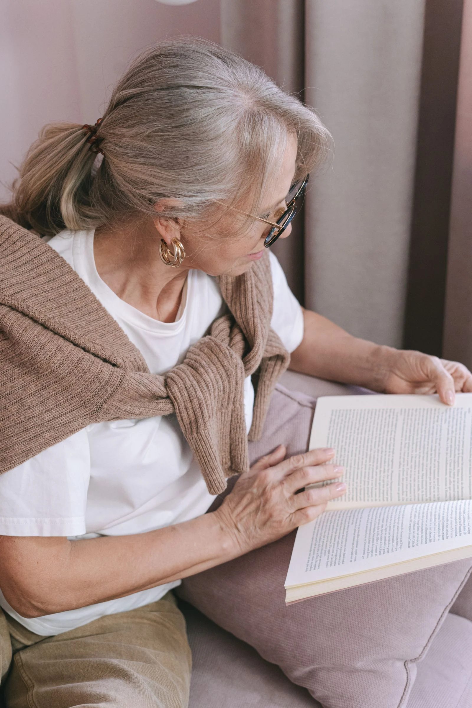 An older woman reading a book at home.