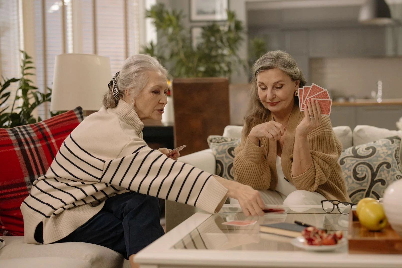 Two older women playing cards at home.