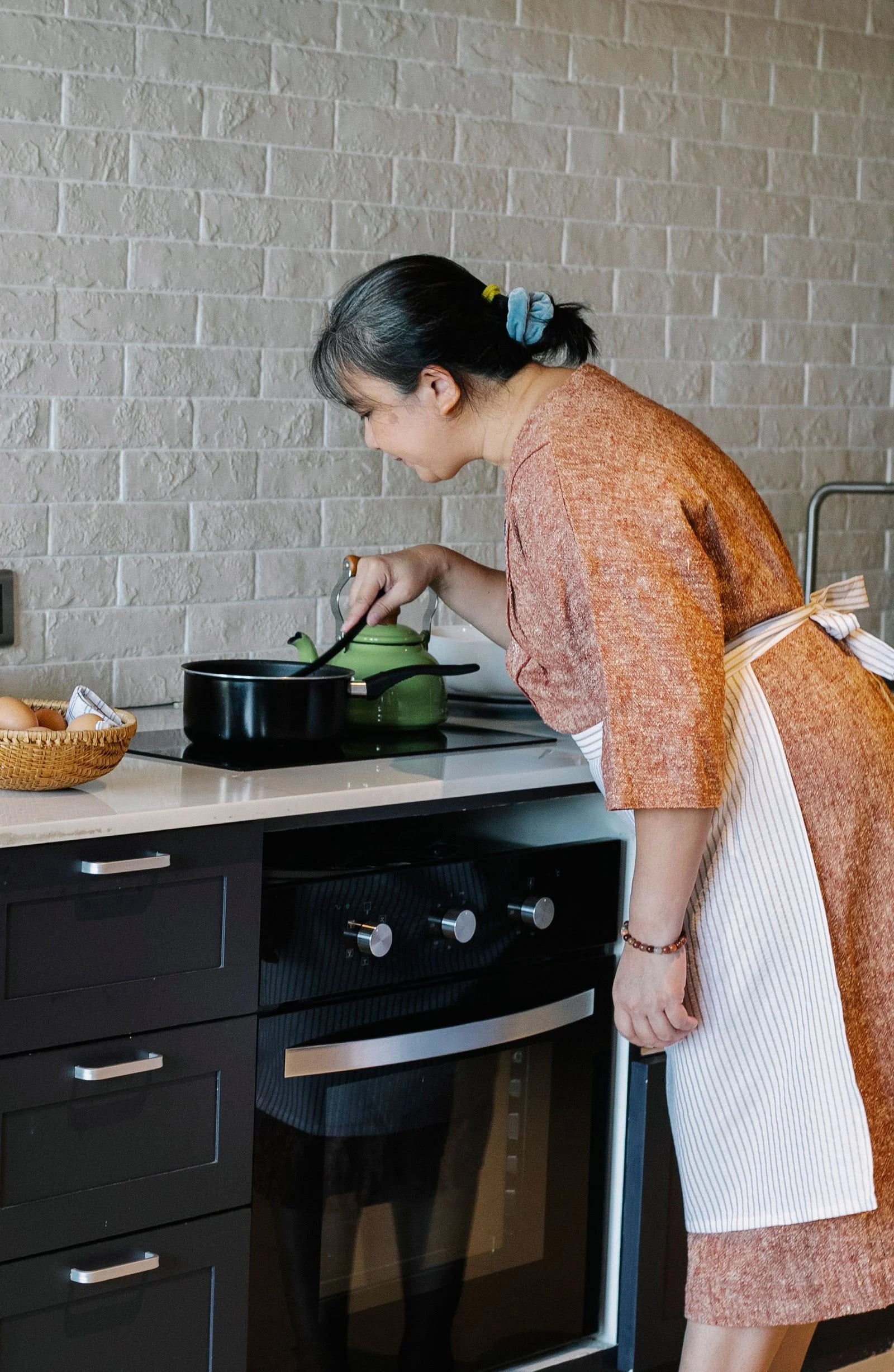 An older woman preparing a meal at the stove.