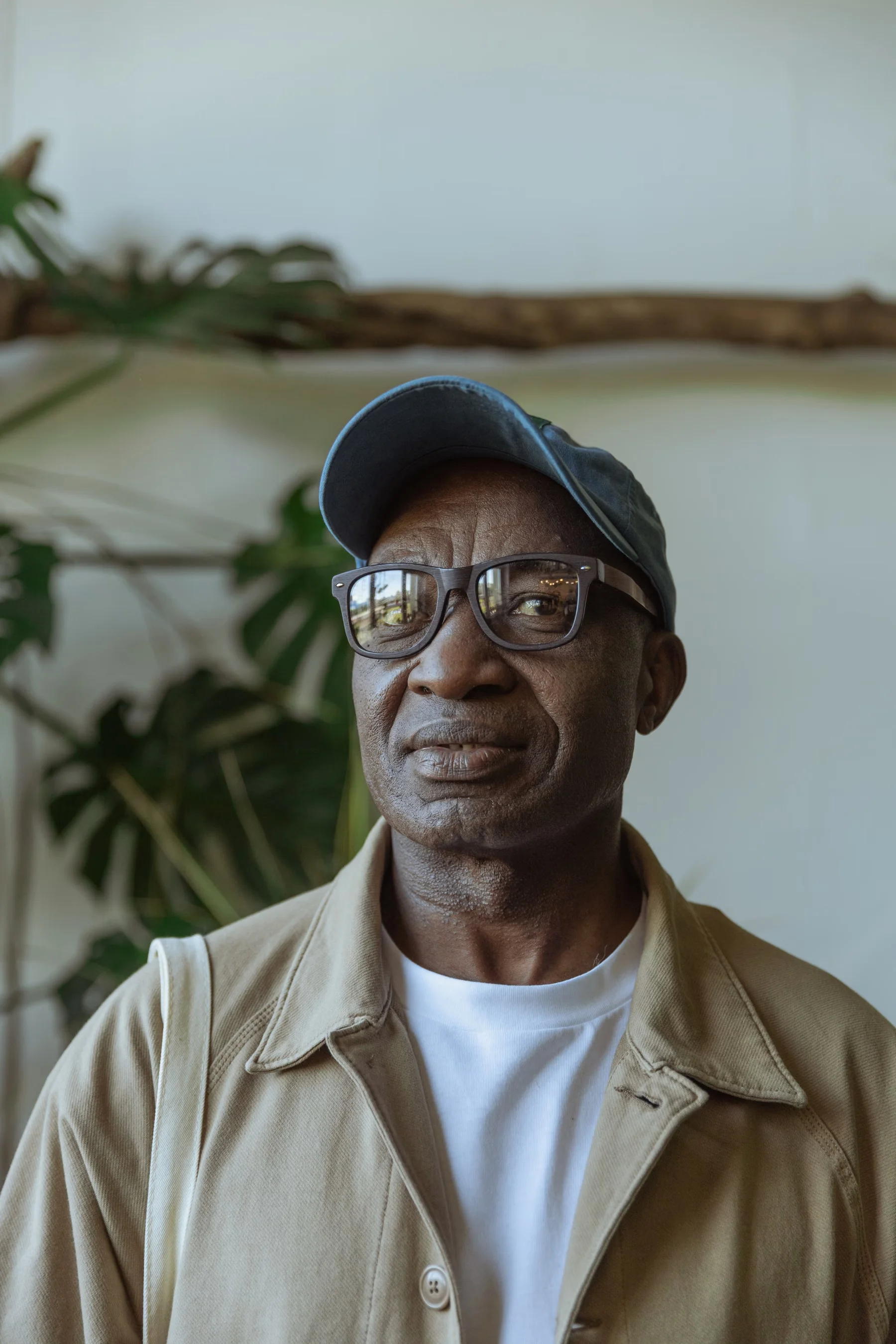 An older man wearing a cap and glasses, relaxing at home.