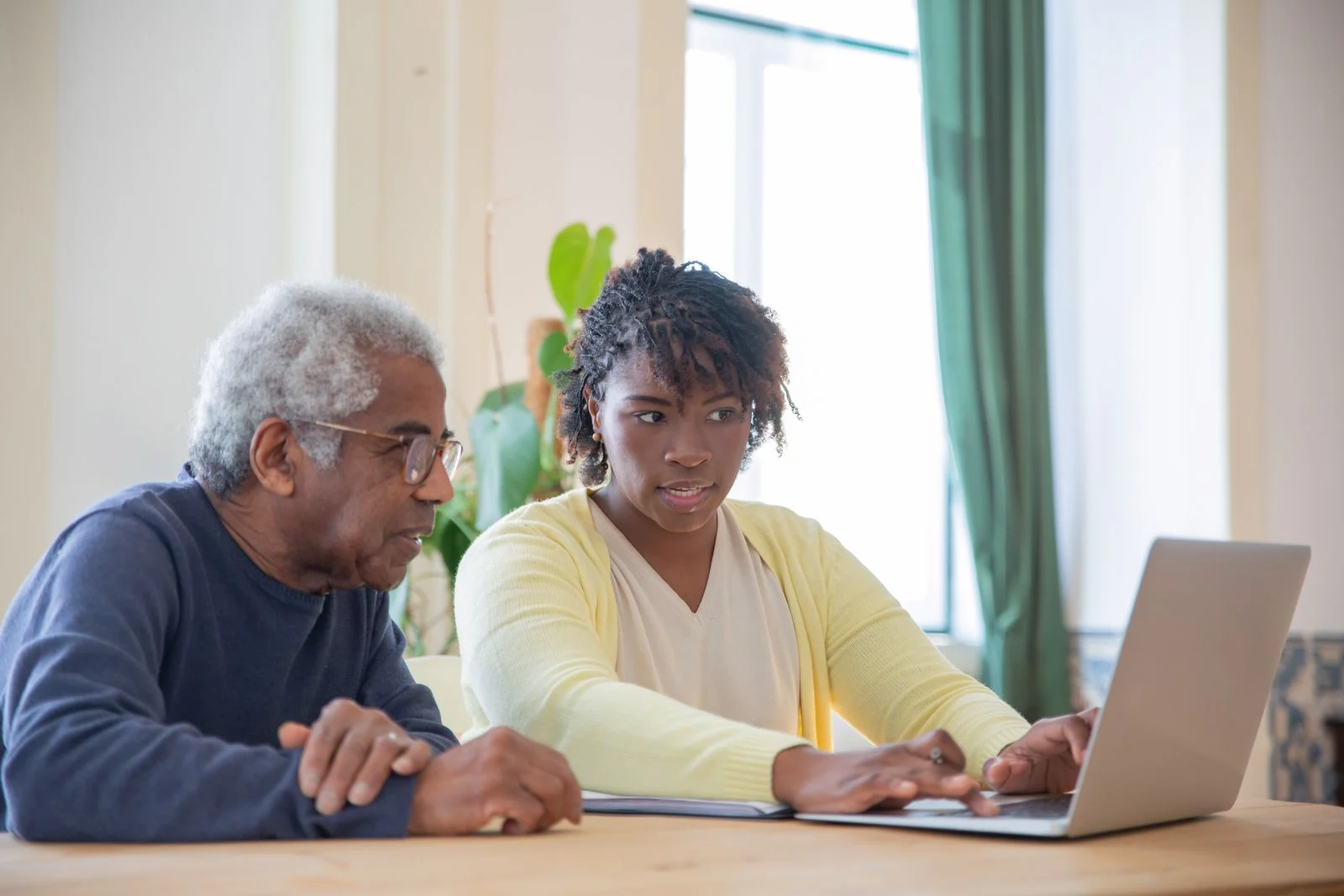 A companion and an older adult looking at a screen together.