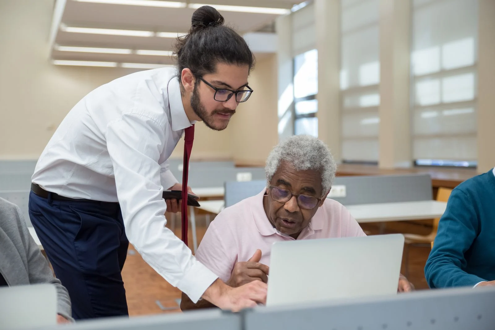 An adult helping an older person use a laptop.